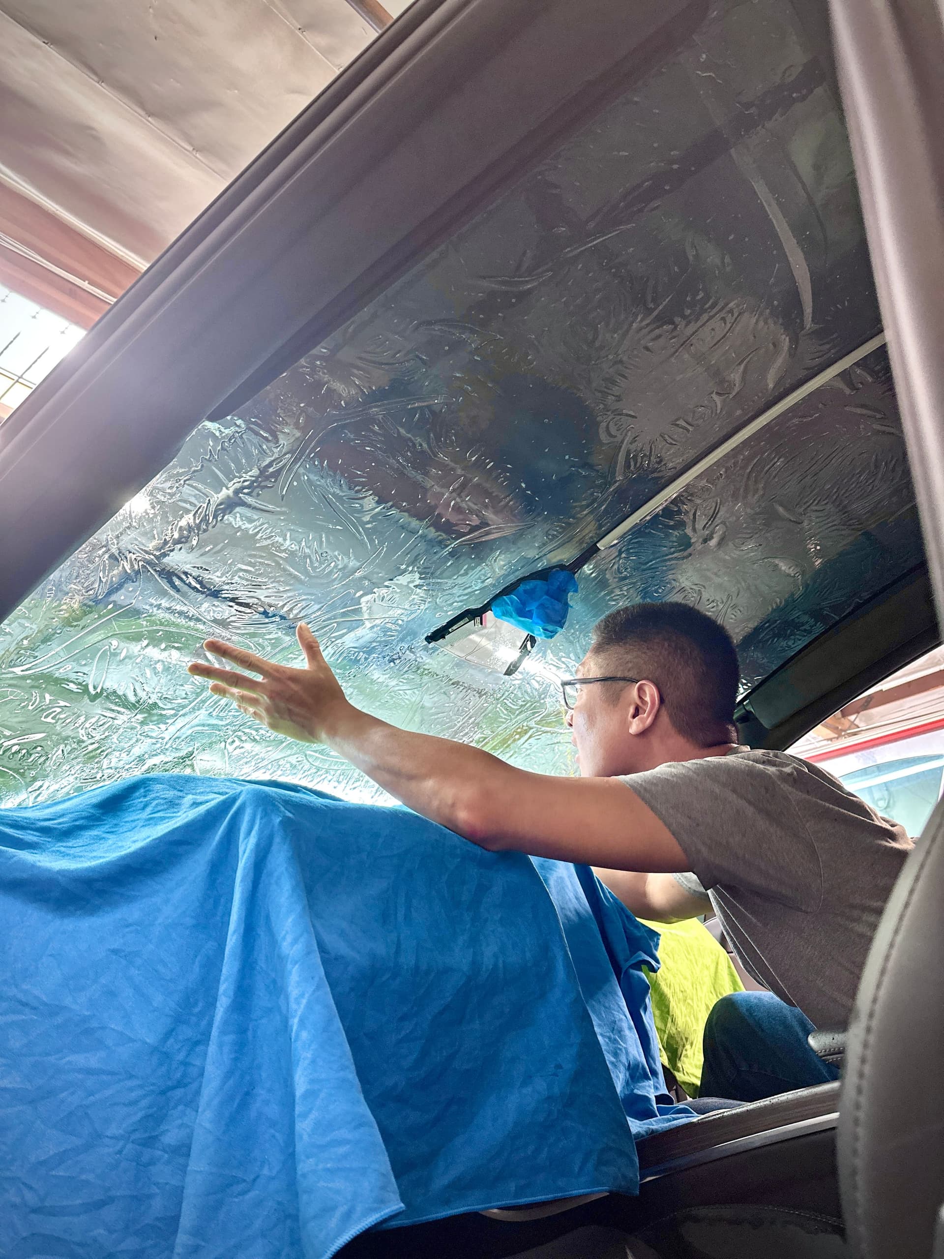 Tint Crew installer hand-laying ceramic film onto a vehicle's windshield